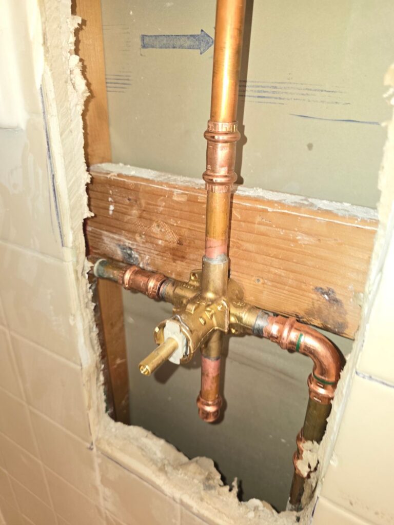 Copper shower valve rough-in plumbing inside an opened wall