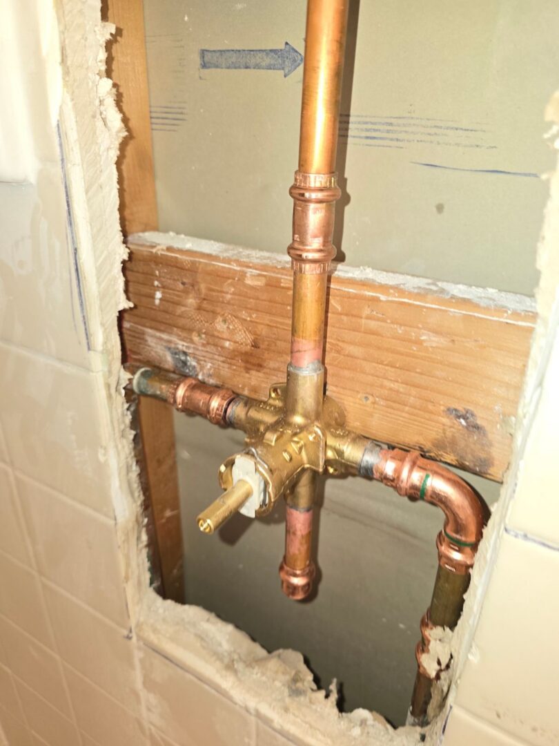 Copper shower valve rough-in plumbing inside an opened wall